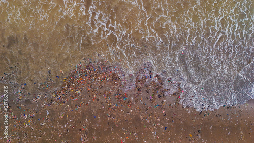 Aerial view of plastic waste and debris washed up on the sandy beach by ocean waves in Indonesia.