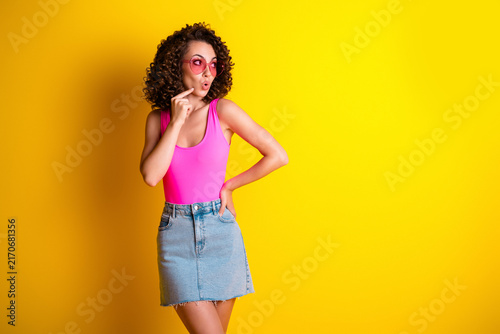 Fotografie Young woman in pink top and denim skirt looking surprised with sunglasses agains