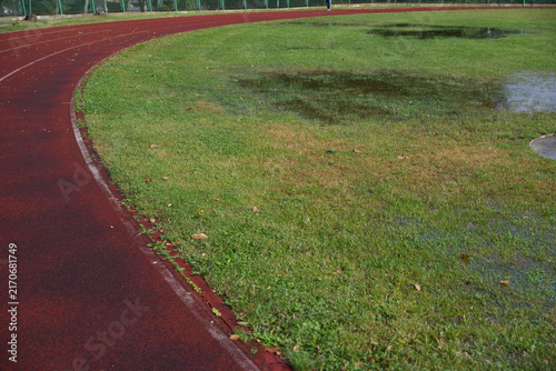Athletics track after heavy rain with flooded grass, making outdoor training difficult in autumn