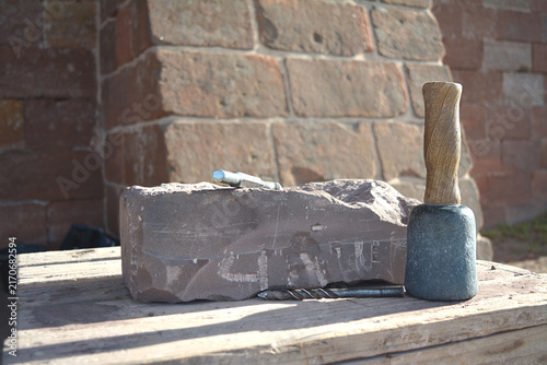 Фотография Stone Carving Tools and Raw Sandstone Block on a Wooden Workbench for Traditiona