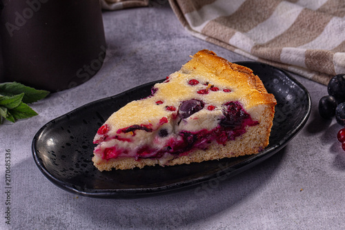 Fotografía Slice of berry pie with blueberry and red currant filling on black plate