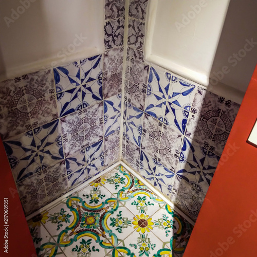 Fotografía Intricate hand painted ceramic tiles featuring vibrant floral patterns and elegant blue geometric designs adorn this corner section of a rustic Mediterranean style villa interior space