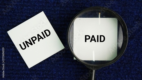 Canvas Print A magnifying glass with the words Paid and unpaid