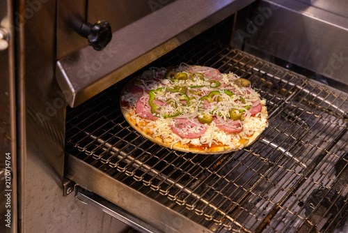 Obraz na płótnie Pizza crua indo para o forno industrial.