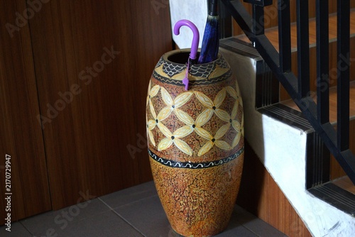 decorative ceramic vase used as an umbrella stand next to a staircase