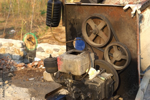 old engine motor with pulleys driving a portable concrete mixer machine