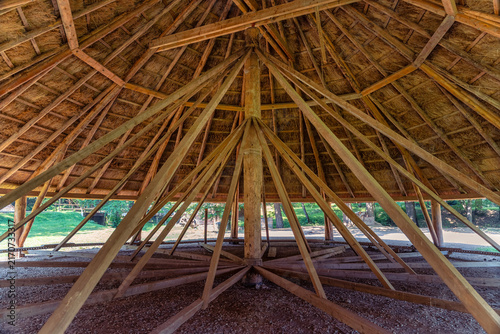 Interior view of radial wooden roof beams beneath a large traditional thatched structure in Romania
