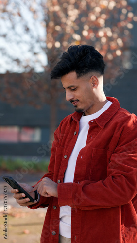 Obraz na płótnie Young Moroccan man engrossed in his mobile phone, connecting and communicating i