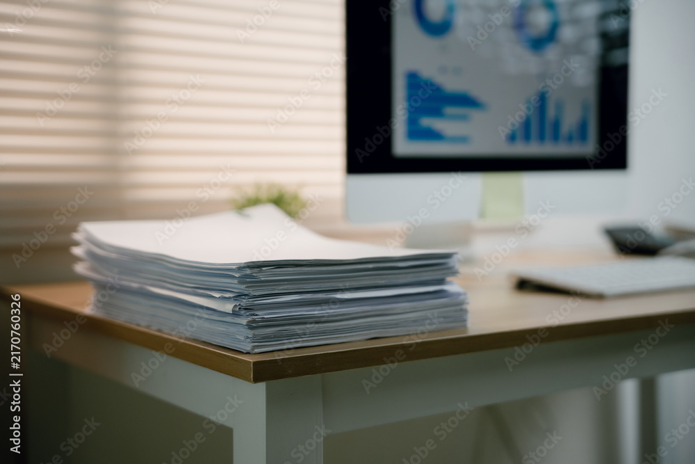 Fototapeta premium Stack of business documents on office desk with computer