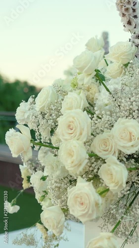 wedding arch of white rose flowers on the river bank before the wedding ceremony of the bride and groom, festive romantic decor