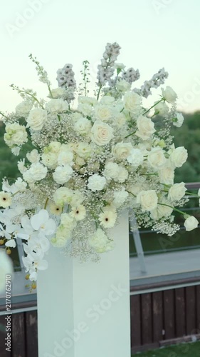 wedding arch of white rose flowers on the river bank before the wedding ceremony of the bride and groom, festive romantic decor
