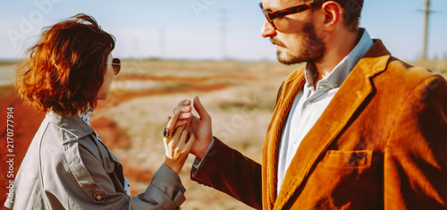Konstfotografi Stylish couple walks through a sunny field surrounded by red grass