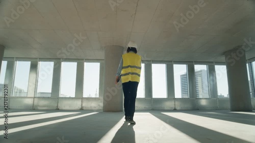 Real Estate Construction Site: Portrait of Female Engineer Architect Walks Through Empty Office Floor, Inspecting Building and Planning Future Interior Layout. Cinematic Low Angle Slow Motion Shot