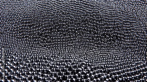 Dense field of small metallic spheres oscillates to form dynamic undulating wave patterns on a dark surface. Animated backdrop combines specular highlights with visible depth.