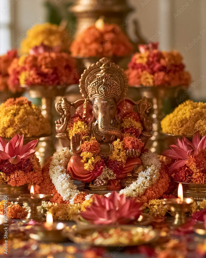 Fototapeta premium Traditional Hindu Ganesha worship altar decorated with marigold flowers, lotus blossoms, garlands and oil lamps, spiritual Indian festival celebration