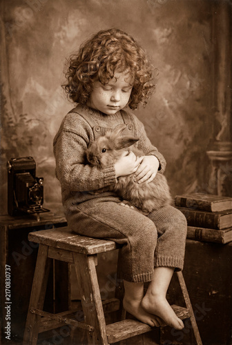 Red-haired child holding a ginger kitten in a vintage interior