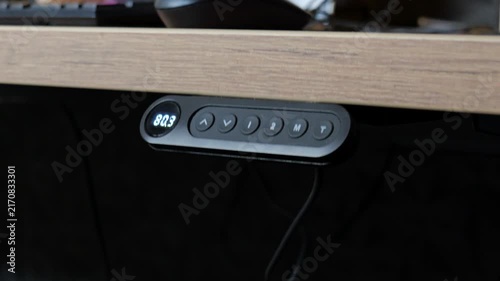 Close up of person pressing button to raise electric standing desk