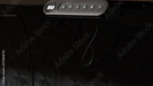Close up of electric standing desk lowering with changing height display