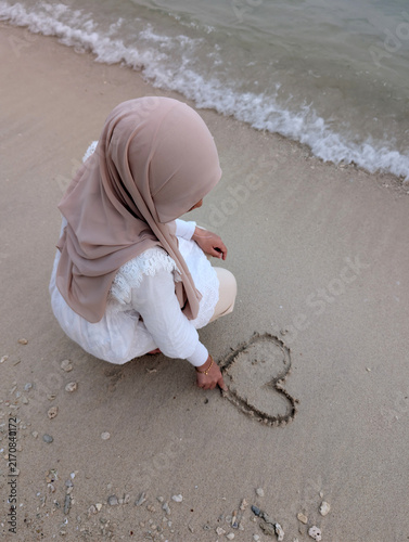 фотографія Woman drawing heart shape on a sand beach