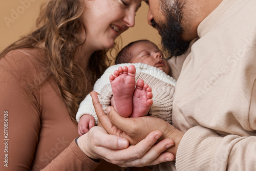 Multiracial Parents Holding Newborn Baby Feet Close-Up, Tender Family Love and Bonding Moment