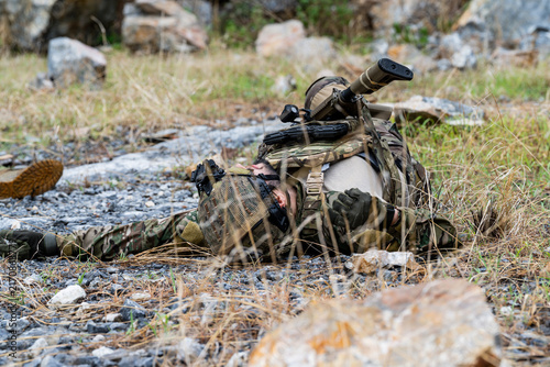 Fotografie Soldier lying on ground during training exercise in rocky outdoor area