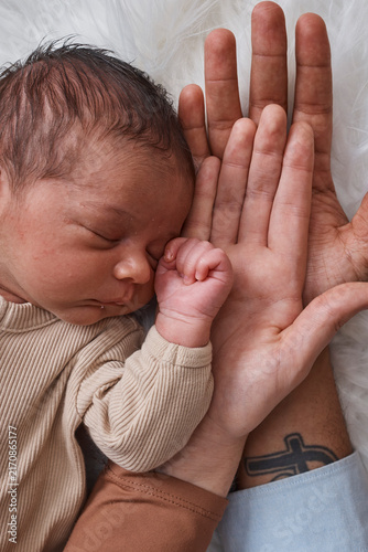 Newborn Baby Sleeping in Parents' Hands With Interracial Family Bond and Gentle Touch
