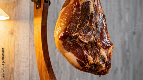 An exquisite Jamón Ibérico, thinly sliced and presented in cascading layers on a wooden board, with a distinct marbled fat content, served with rustic bread, tomato spread, and a glass of Rioja wine, 