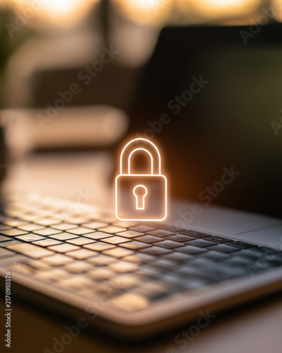 Cybersecurity Symbol on Laptop: A glowing, stylized padlock icon hovers over the keyboard of a modern laptop, symbolizing digital security and data protection in a warm, abstract light.