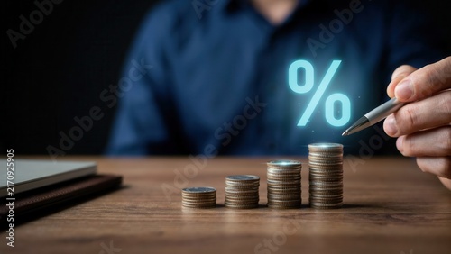 Professional hand holding metallic pen above stacked gold coins with digital glowing percentage symbol showing rising financial interest rate growth