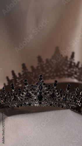 Elegant Black Crystal Tiara on Beige Gold Fabric. Luxurious royal accessory with sparkling gemstones and intricate metalwork, creating a sophisticated and glamorous atmosphere. 