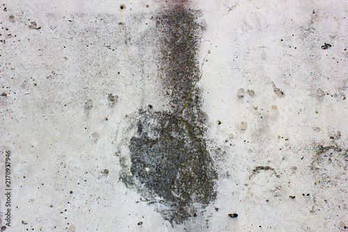A gray concrete wall with a dark spot. A concrete wall stained with mold and mildew. An authentic wall, design.