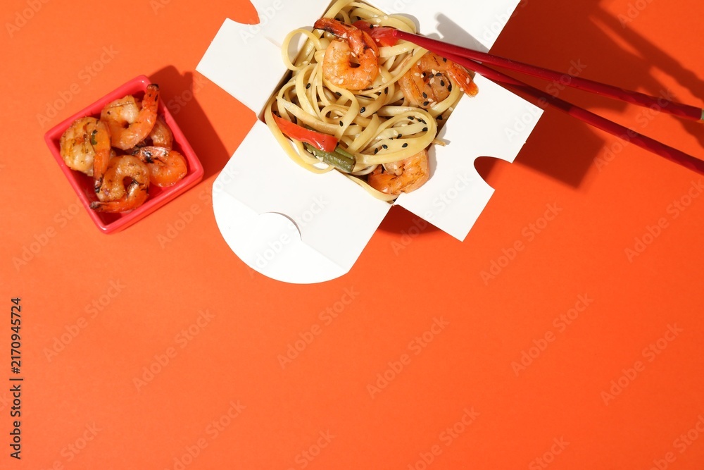 Naklejka premium Delicious wok with shrimps in takeaway box on orange background, top view. Space for text
