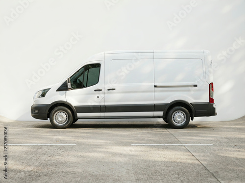 White high roof commercial van in side view against a plain light wall