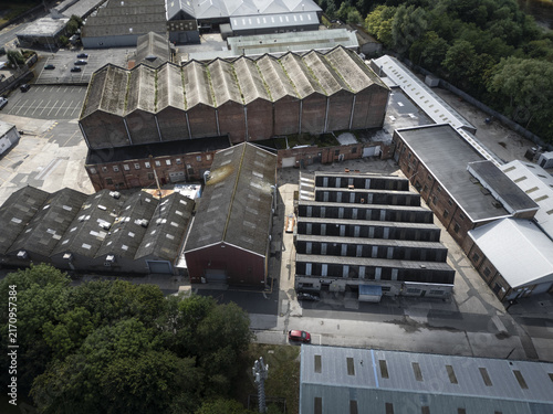 Aerial view of industrial warehouses with sawtooth roofs and brick facades situated in an urban area in Lancaster, England, United Kingdom.