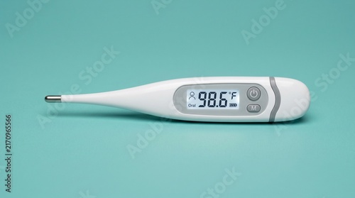 Digital medical thermometer displaying normal body temperature on teal background.