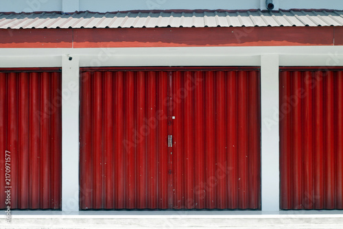 Red Garage Doors And Metal Storage Units On White Building Facade With Symmetrical Design