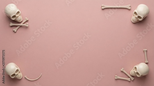 Human skulls and bones arranged as a frame on a solid pink background