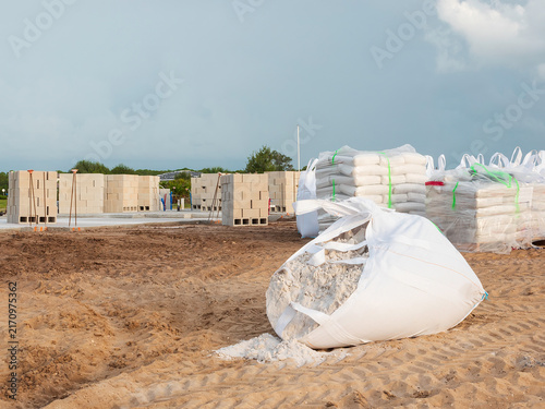 Bags of masonry cement near stacks of concrete blocks for construction of a hurricane-resistant single-family house on a concrete foundation in a suburban residential development in southwest Florida