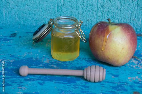 Honey in a jar, apple and honey dipper on blue background