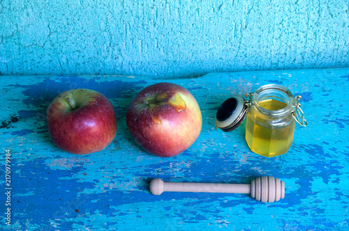 Honey in a jar, apple and honey dipper on blue background