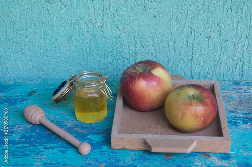 Honey in a jar, apple and honey dipper on blue background