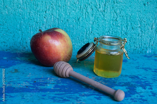 Honey in a jar, apple and honey dipper on blue background