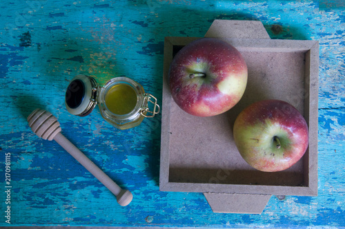 Honey in a jar, apple and honey dipper on blue background