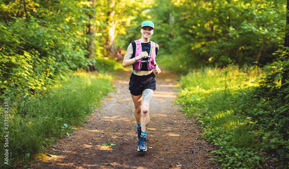 Fototapeta premium Young woman track suit running on the forest trail on summer
