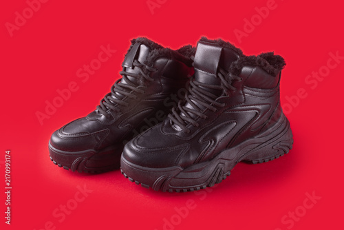 Leather classical sport shoes with fur isolated on red background. Winter high lace-up boots.
