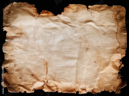 Old crumpled vintage paper sheet with burned torn edges and rich texture. Heavily damaged antique paper with creases, stains and wear, isolated on black background. Perfect overlay texture for design