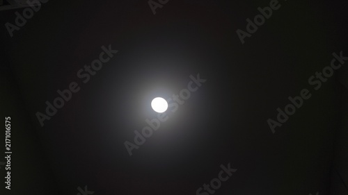 Quadro su tela A single bright white light glowing in the center of a dark background