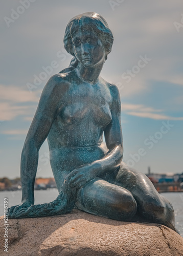 Little Mermaid statue, a bronze sculpture depicting the fairy tale character, sitting on a rock by the water, attracting tourists and symbolizing Copenhagen's cultural heritage