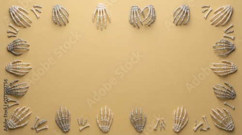 Plastic skeleton hands arranged in a frame on a pale yellow background