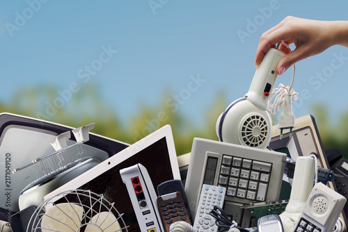 Foto E-waste Recycling with Hand Placing Vintage Hairdryer on Pile of Electronics Out